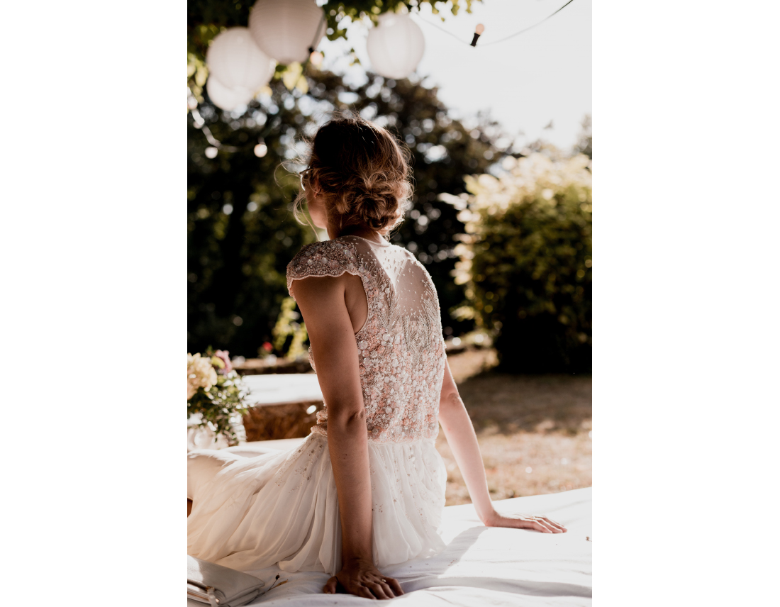 La mariée de dos avec sa robe brodée de perles.