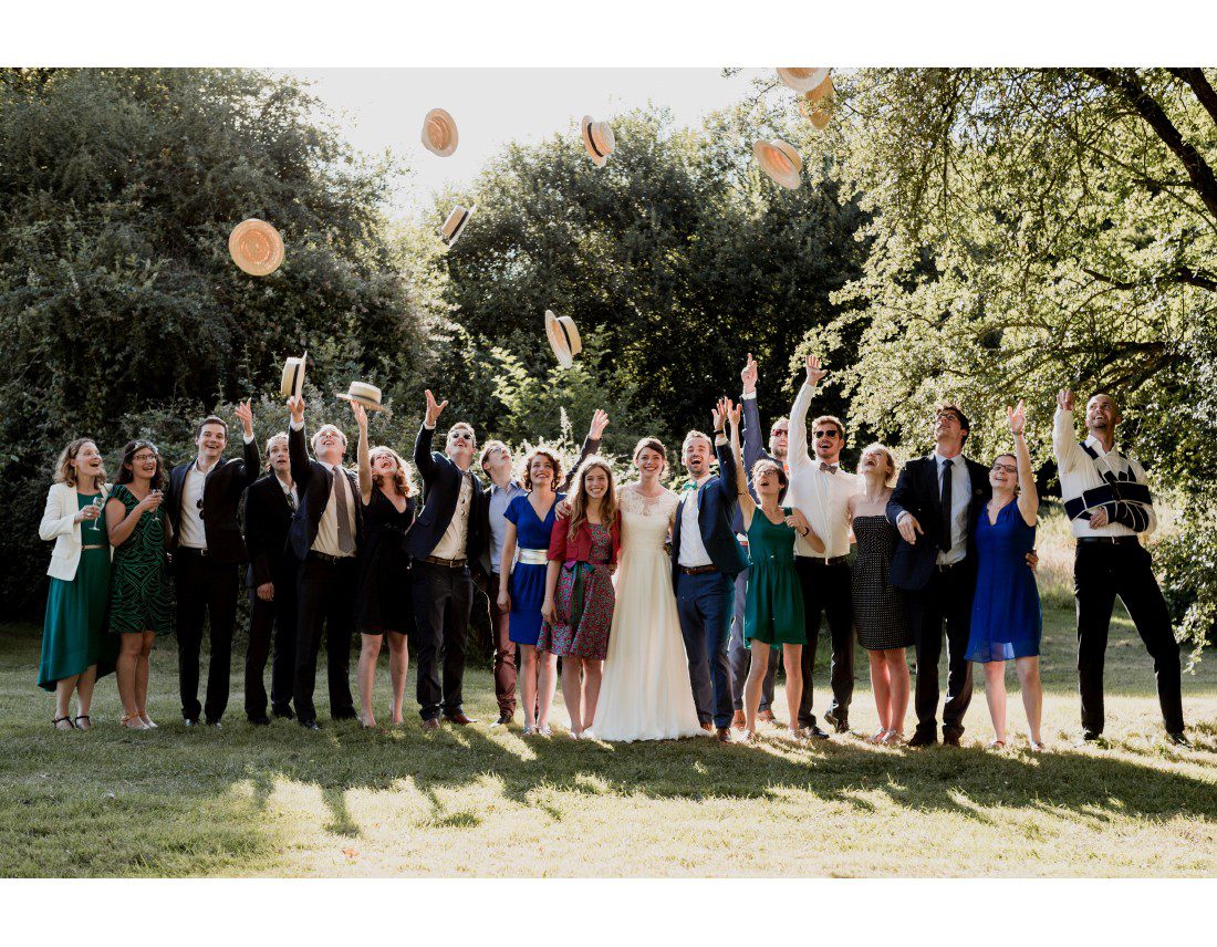 Photo de famille lors d'un mariage avec chapeau lancés en l'air.