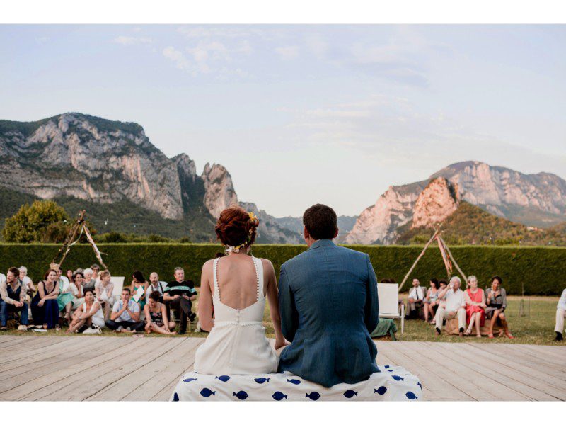 Mariés assis de dos face aux montagnes.