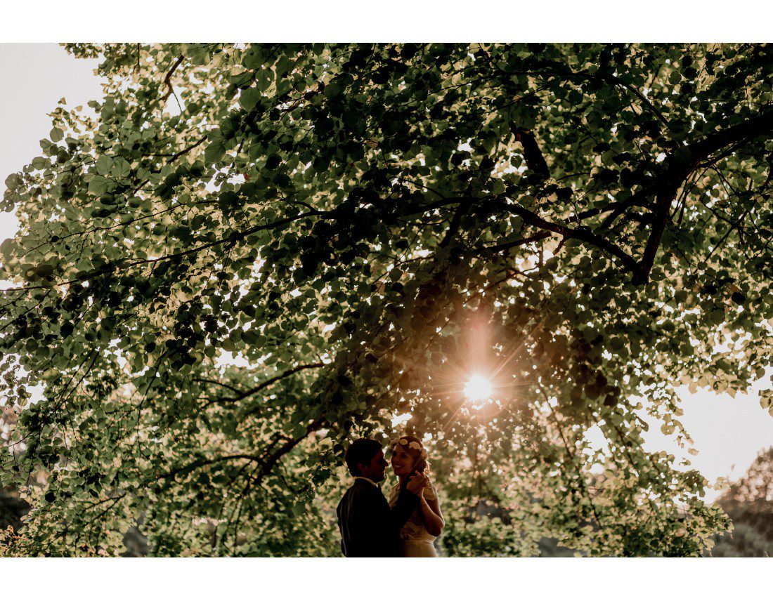 Couple de mariés dans le soleil couchant et arbres.