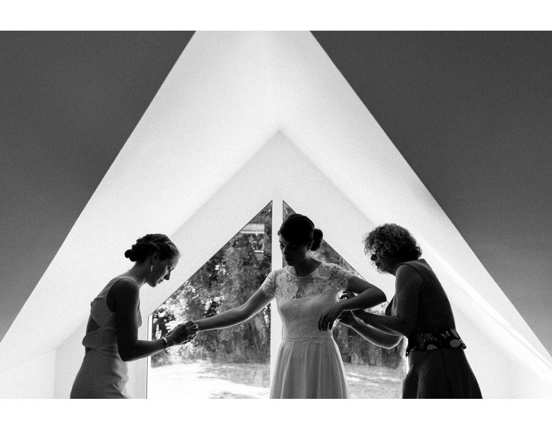 Habillage de la mariée devant une fenetre triangulaire.