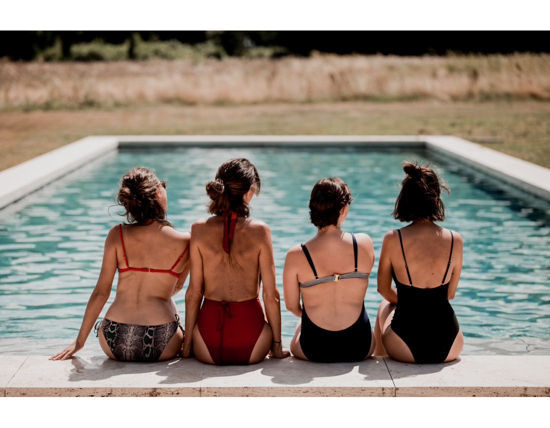 4 filles de dos en maillot au bord de la piscine