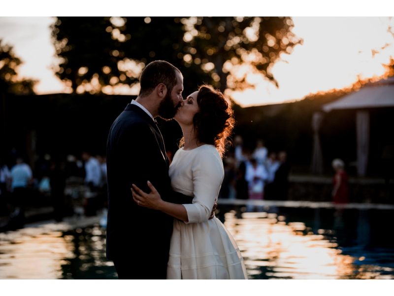 Couple de mariés qui s'embrasse au coucher de soleil devant la piscine du chateau de courban.
