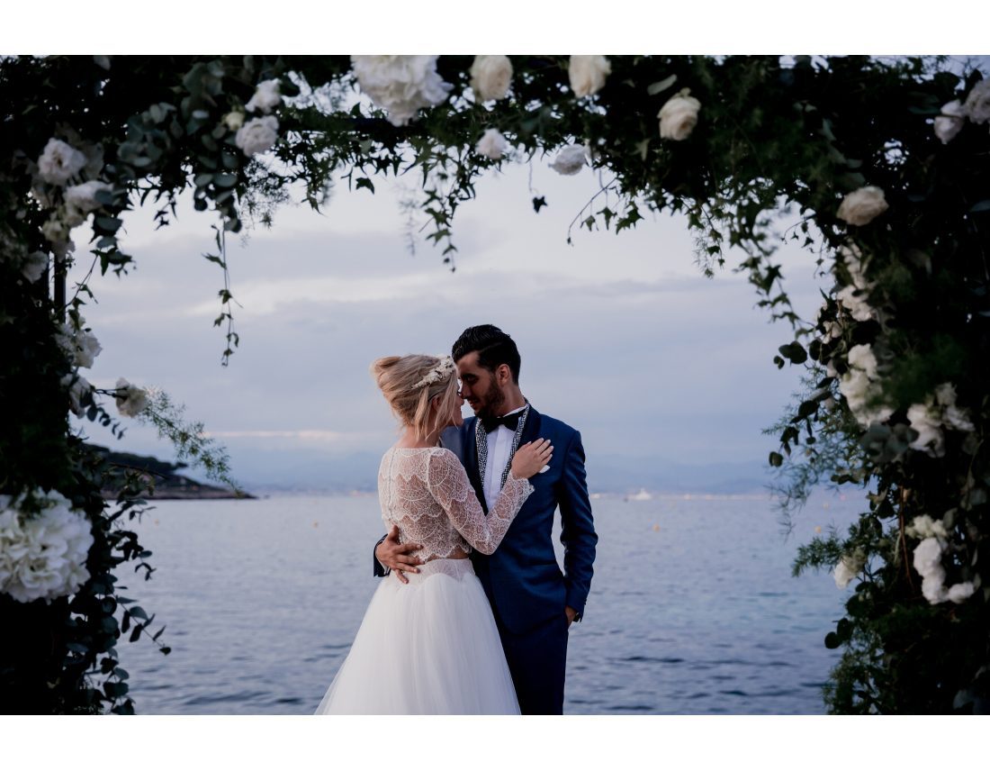 Couple de mariée devant la mer, arche de fleur.