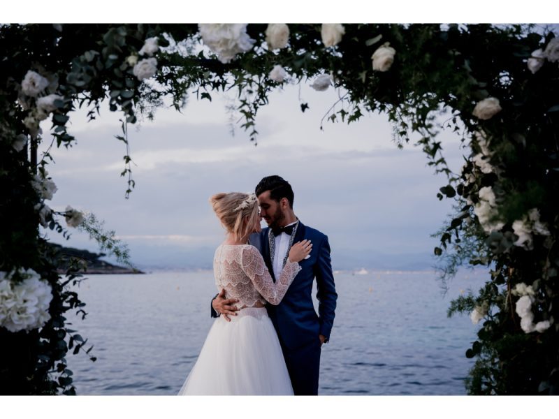 Couple de mariée devant la mer, arche de fleur.